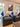 Pair of Evan chairs in dark textured upholstery with patterned pillows, arranged in a living room.